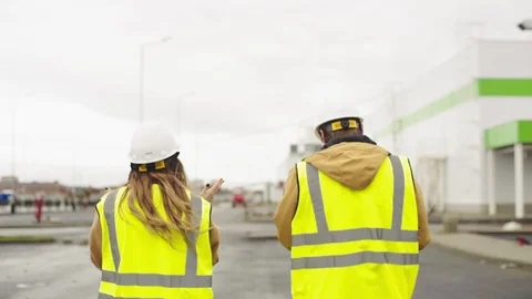 Female engineer and builder walk along construction site Stock Footage 123930764