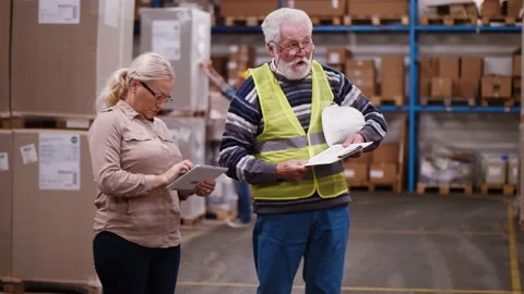 Female engineer and an old worker walk warehouse Stock Footage 166704162