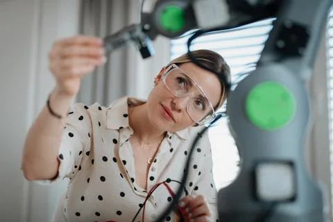 Female engineer building and programming a robotic arm at home. Foto stock