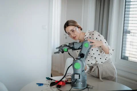 Female engineer building and programming a robotic arm at home. Foto stock