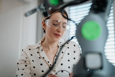 Female engineer building and programming a robotic arm at home. Fotos de archivo