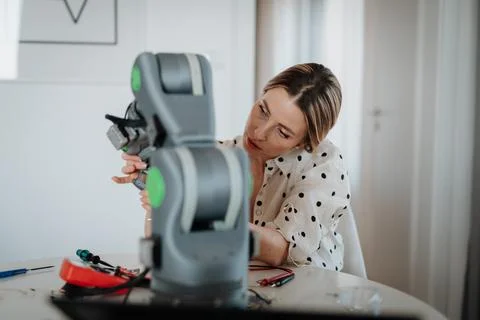 Female engineer building and programming a robotic arm at home. Foto stock