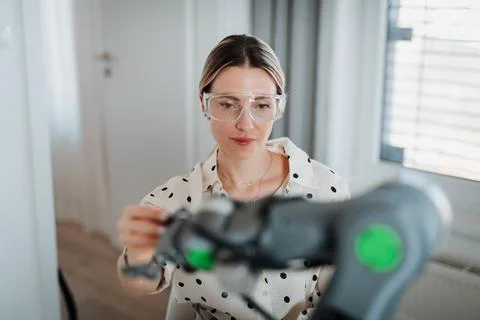 Female engineer building and programming a robotic arm at home. Fotos de archivo