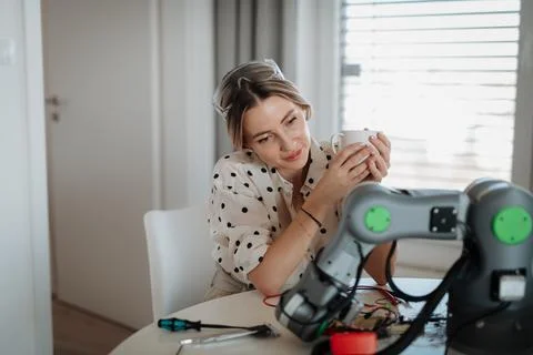 Female engineer building and programming a robotic arm at home. Foto stock