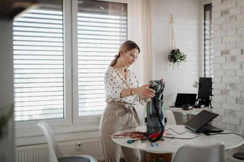 Female engineer building and programming a robotic arm at home. Stock Photos
