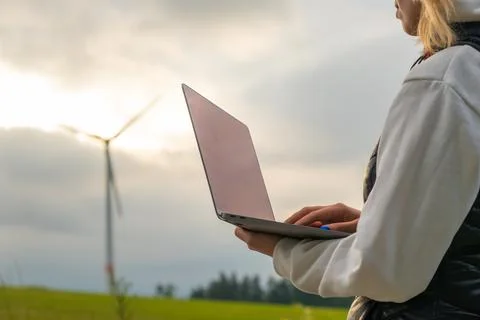 Female engineer checking the stability work of windmill in the field at sunlight Stock Photos