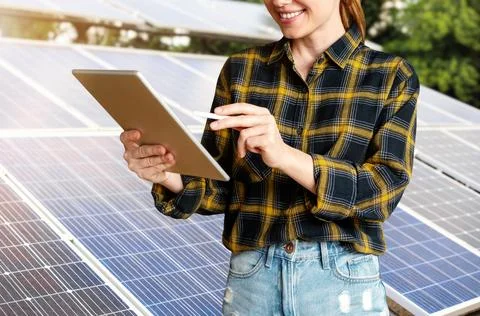 Female engineer checks the technical condition of solar panels using a digita Stock Photos
