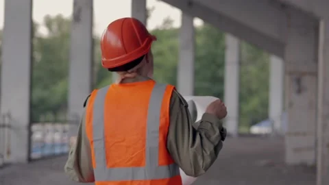 A female engineer is on the construction site and look at the drawing Stock Footage 134287420