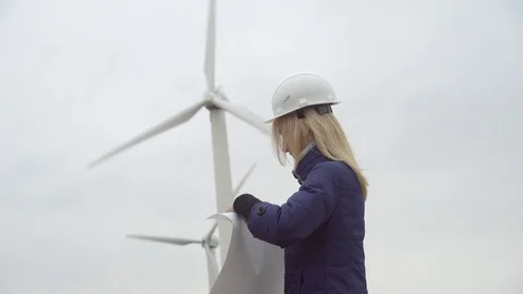 Female engineer controls the work of wind generators. Considers drawing Stock Footage 118195683