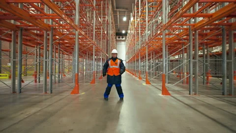 Female engineer dances on aisle between empty metal racks Stock Footage 201918071