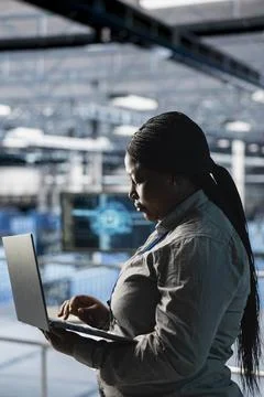 Female engineer in data center using laptop to configure hardware for AI tasks Foto stock