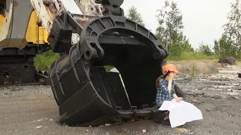 Female engineer examines a scheme sitting in a large bucket of a excavator. Stock Footage 80207161