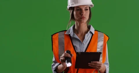 Female engineer in hard hat shining flashlight into camera lens on greenscreen Stock Footage 85502869