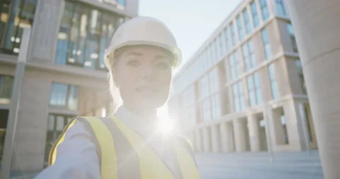 Female engineer in hardhat making video call to client standing outdoors at Stock Footage 156447988