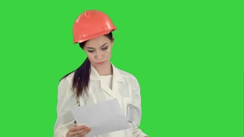 Female engineer in helmet reading contract and nodding her head on a Green Vídeos de archivo 71754760