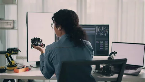 Female engineer holding robotic prototype while working with laptop. Stock Footage 319001227