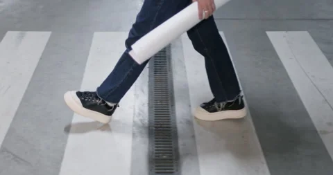 Female engineer holds rolled project walking on crosswalk Stock Footage 273583383