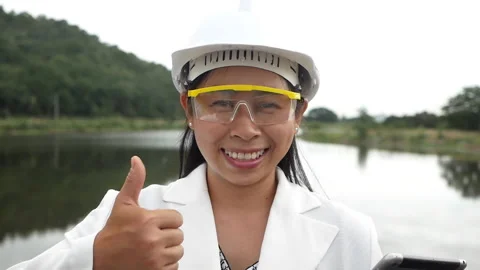 Female engineer holds a tablet with her thumb up at a dam. Stock Footage 156528952