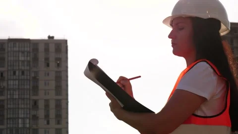 Female engineer inspecting construction site, reviewing plans and taking notes Stock Footage 347955098