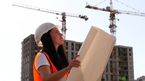 Female engineer inspecting construction site and reviewing blueprints during Stock Footage 348560710
