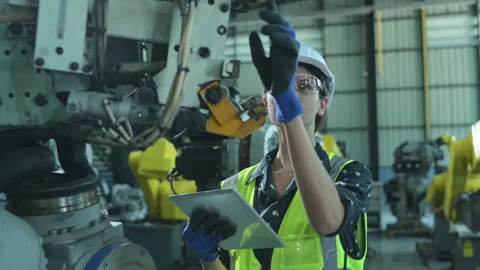 A female engineer installs a program on a robotics arm Stock Footage 241099153