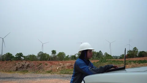 Female engineer with laptop in front of wind turbine Stock Footage 127912900
