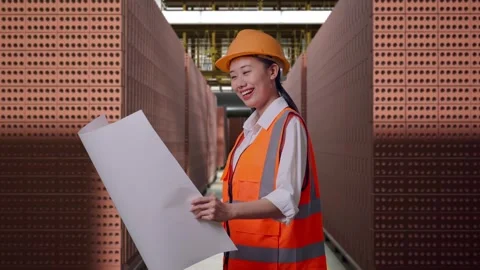 Female Engineer Looking At Blueprint In Her Hands With Brick In Stacks Stock Footage 303762082