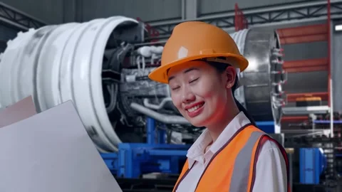 Female Engineer Looking At Blueprint In Her Hands With Jet Engine Stock Footage 306605535