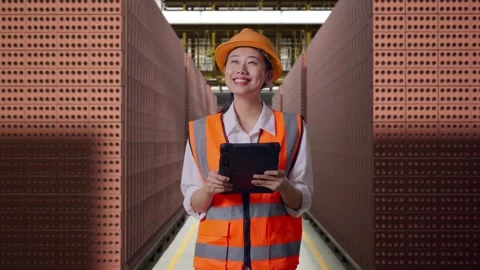 Female Engineer Looking At The Tablet In Her Hand With Brick In Stacks Stock Footage 303761812