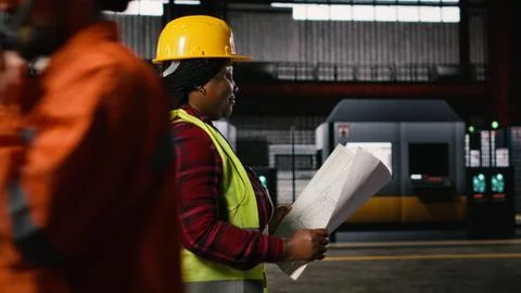 Female engineer, manufacturing blueprints, technical circuits, large factory Stock Photos