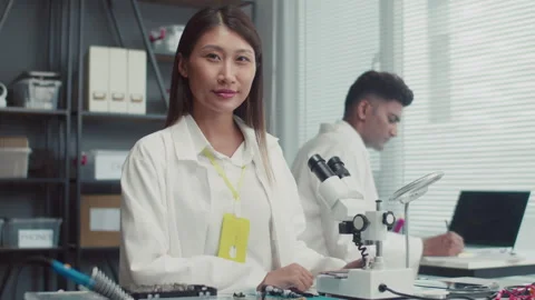 Female Engineer with Microscope Looking at Camera Stock Footage 261661195
