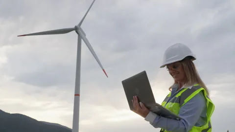 A female engineer observes wind turbines, dreaming of a cleaner and more Stock Footage 272641850