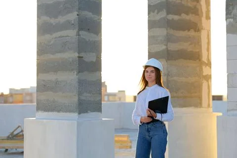 Female engineer pointing at construction site while holding clipboard Stockfoto's