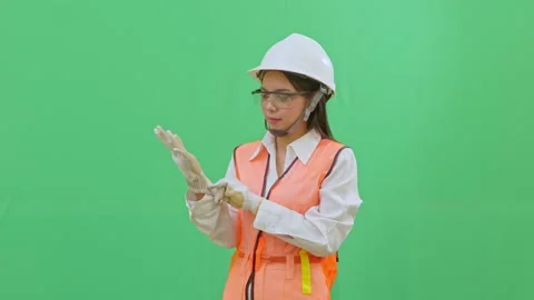 Female engineer pulling on a safety glove on her right hand. Vídeos de archivo 332057192