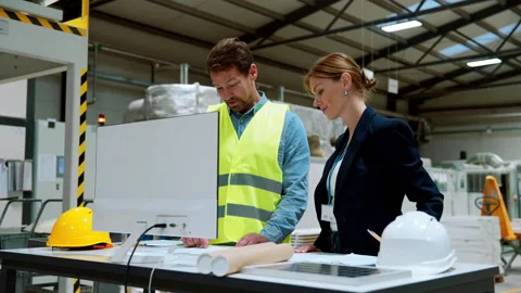 Female engineer reading technical documentation with project manager in modern Stock Footage 260654480