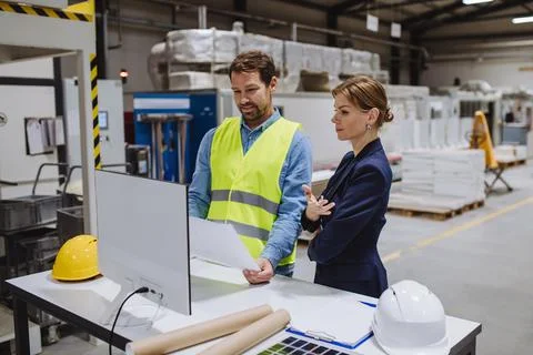 Female engineer reading technical documentation with project manager in modern 스톡 사진