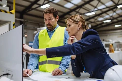 Female engineer reading technical documentation with project manager in modern Stockfoto's