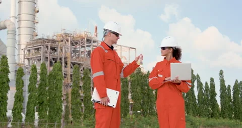Female engineer reviews sample beside male technician with laptop at refinery Stock Footage 344394936