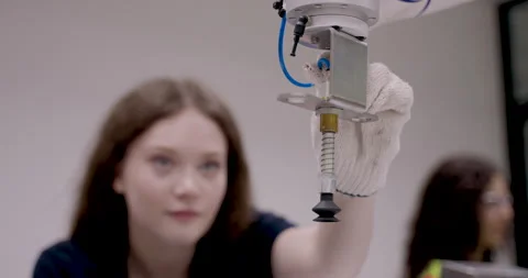 Female engineer in safety gloves carefully positions object below robotic Stock Footage 313648448
