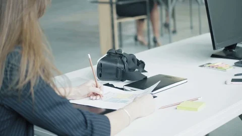 A female engineer sits at a desk and adjusts the drawing with a pencil Stock Footage 124327687
