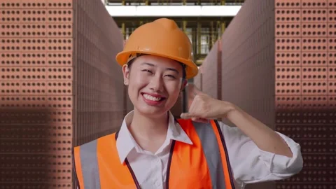 Female Engineer Smiling And Making Call Me Gesture With Brick In Stacks Stock Footage 303762358