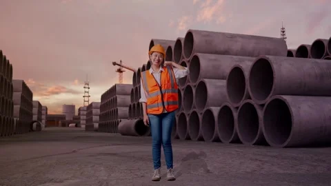 Female Engineer Smiling And Making Call Me Gesture with Concrete Pipes Stock Footage 324500357