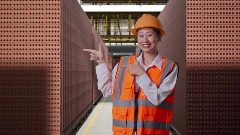 Female Engineer Smiling And Pointing To Side With Brick In Stacks Stock Footage 303761664