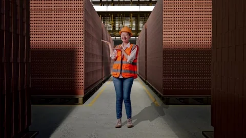 Female Engineer Smiling And Pointing To Side With Brick In Stacks Stock Footage 303762944