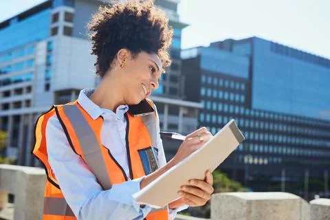 Female Engineer Smiling and Taking Notes on Construction Site in City Foto stock