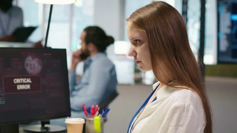 Female engineer in startup office struggling to fix critical error warning popup Stock Footage 313015448