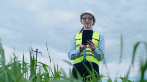 A female engineer stops on the road in front of a high voltage power line, takes Stock Footage 241801690