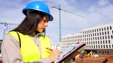 Female engineer supervising a construction site and taking notes Stock Footage 334577873