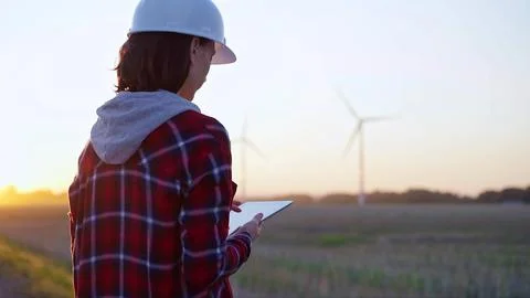 Female engineer taking notes with a tablet computer on a field with wind Foto stock