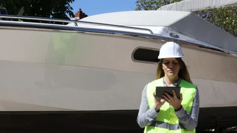 Female engineer use tablet for test and checking of a motorboat at shipyard. Stock Footage 153074692